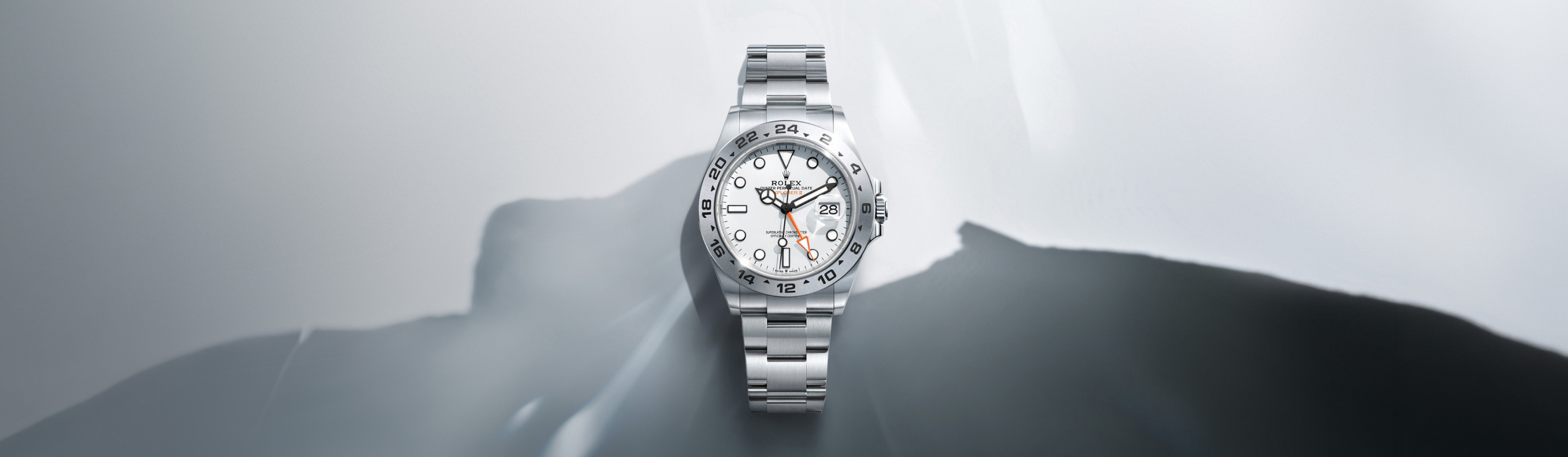A gold and silver wristwatch with a black dial and Arabic numerals for 3, 6, and 9 lies against a gradient gray background.